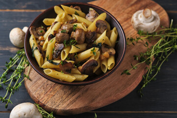 Vegetarian pasta with mushrooms, chickpeas, spinach, spices and herbs. Italian pasta in a bowl on an old wooden table.