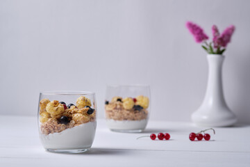 Muesli with yogurt and fresh berries served in a glass. Breakfast on a white wooden table.