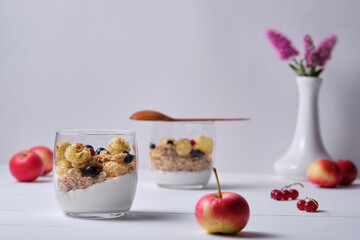 Muesli with yogurt and fresh berries served in a glass. Breakfast on a white wooden table.