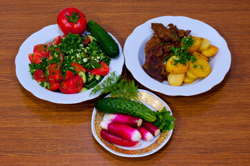Meat with potatoes and vegetable salads.