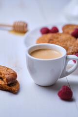 Morning espresso with honey cookies and raspberries. Breakfast on the white kitchen table.