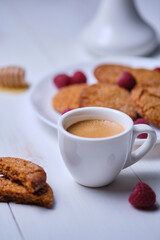 Fototapeta na wymiar Morning espresso with honey cookies and raspberries. Breakfast on the white kitchen table.