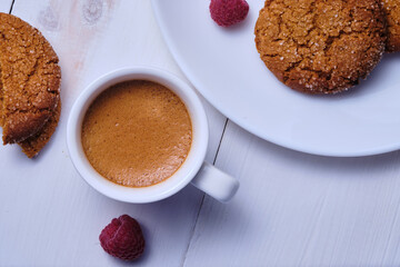 Morning espresso with honey cookies and raspberries. Breakfast on the white kitchen table.