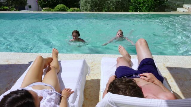 WS Children (12-13, 14-15) splashing parents relaxing on poolside 
