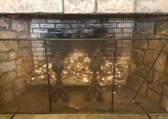 fireplace with metal fence and holiday lights