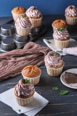 The process of making holiday cupcakes with pink cream. The dessert is decorated with mint leaves and chocolate chips. Background color classic blue.