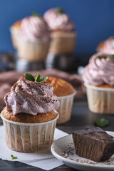The process of making holiday cupcakes with pink cream. The dessert is decorated with mint leaves and chocolate chips. Background color classic blue.