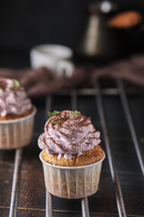 Holiday cupcakes with pink cream. The dessert is decorated with mint leaves and chocolate chips. Cupcakes and coffee. Background color classic blue.