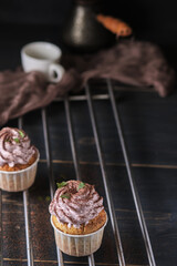 Holiday cupcakes with pink cream. The dessert is decorated with mint leaves and chocolate chips. Cupcakes and coffee. Background color classic blue.