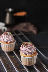 Holiday cupcakes with pink cream. The dessert is decorated with mint leaves and chocolate chips. Cupcakes and coffee. Background color classic blue.