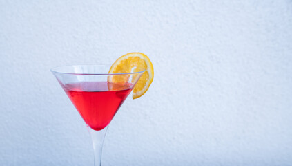 A red drink with a slice of orange in a cocktail glass 