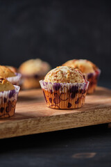 Cupcakes with berries and chocolate on a large wooden board. Fresh dessert on a dark old wooden table.