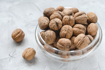 Uncracked walnuts in shell in bowl on gray background, concept of healthy eating vegan food. Close up, selective focus, copy space
