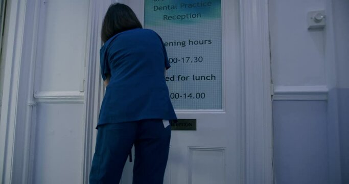 WS Woman unlocking door and entering in dentist's office / Hove, Sussex, UK