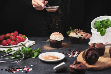 The process of making cupcakes. Hands of the cook in the frame. Dessert with cream, fresh berries, chocolate and mint. Chocolate ganache stuffed muffins.