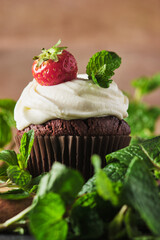 Cupcakes with cream, fresh berries, chocolate and mint, decorated with cocoa. Chocolate ganache stuffed muffins.