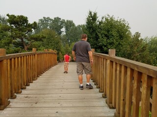 father and son and trees with green leaves and wooden bridge