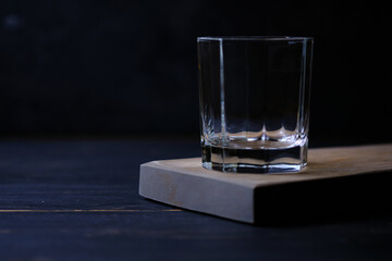 Empty glass on a wooden board in a bar. Waiting for whiskey to be poured into it.