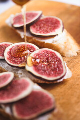 Bruschettas with figs, soft cheese and honey on a wooden board.
