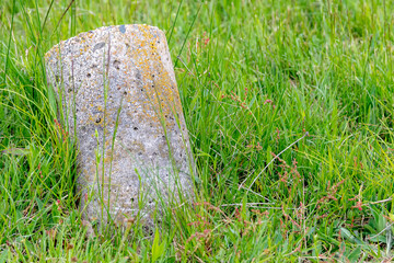 A small concrete cylinder resting at an angle in a field.