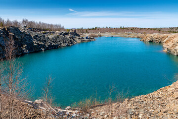 An old quarry filled with water, making it a pond. The water is bluish green, with the sky above.