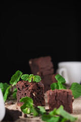 Chocolate brownie with nuts and mint. Sweet and tasty dessert decorated with mint, closeup on a wooden table. Soft focus.
