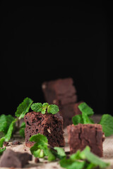 Chocolate brownie with nuts and mint. Sweet and tasty dessert decorated with mint, closeup on a wooden table. Soft focus.