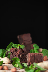Chocolate brownie with nuts and mint. Sweet and tasty dessert decorated with mint, closeup on a wooden table. Soft focus.