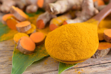 Turmeric (curcumin) powder,leaves and root on wooden background,copy space.