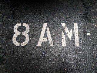 Fototapeta na wymiar eight or 8 AM in white stencil on black asphalt