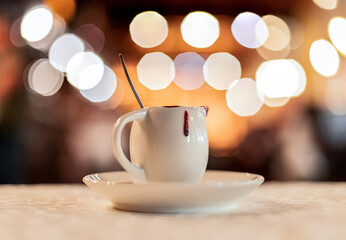 soft focus noise polluted concept picture in cafe still life with cup of coffee on table and lamp illumination light unfocused inside background