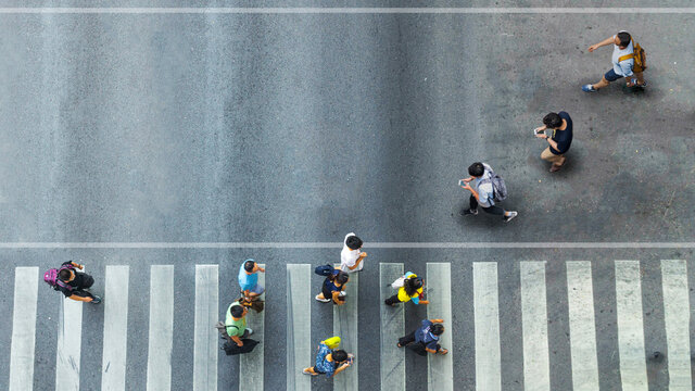Human life in Social distance. Aerial top view with blur man with smartphone walking converse with busy city crowd move to pedestrian crosswalk