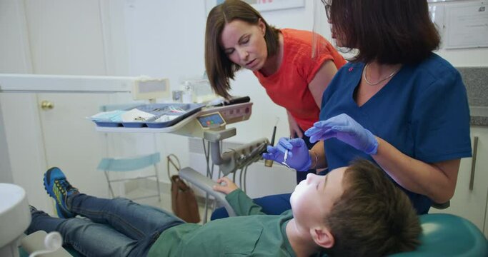 MS Dentists checking boy's (8-9) teeth during appointment and talking to mother / Hove, Sussex, England, United Kingdom