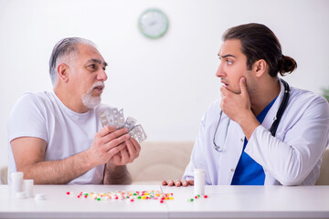 Young male doctor visiting old male patient at home