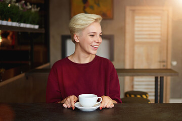 Caucasian young female enjoying cappuccino drink in coffee shop