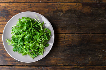 Arugula rocket salad on a plate against wooden background