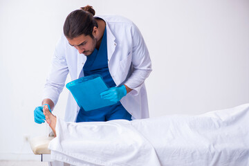 Police coroner examining dead body corpse in morgue