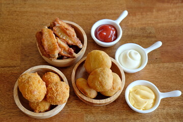 Assortment of fast food products : lasagna, french fries, fried chicken, cheese balls, nuggets  with sauce on table background