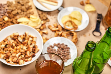 Drinking beer after work. Table full of beer snacks. Pouring bottle of cold beer into glass. Celebrating international beer day, Octoberfest, friends celebrate meeting