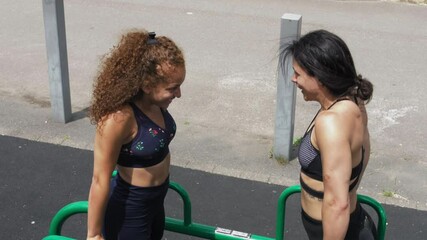 MS Two Young women exercising on monkey bars / UK - Powered by Adobe