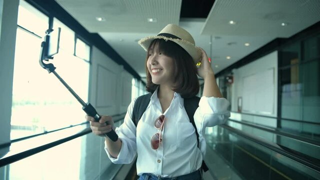 Tourism concept. An Asian woman is calling a video call inside the airport. 4k Resolution.
