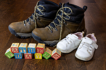 happy fathers day message written out with children's wooden blocks with adult and kids shoes in the background