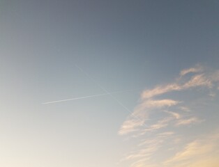 Fototapeta na wymiar contrail or trail of planes in the blue sky with clouds in a crossing x shape