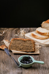 Close up Homemade delicious freshly baked classic sweet banana bread sliced with blueberry/strawberry jam and butter knife on a wooden kitchen Table in rustic style.Ideas recipe healthy diet breakfast