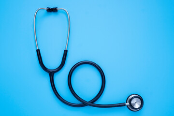 Close-up of Black stethoscope of doctor for checkup on blue background. Stethoscope equipment of medical use to diagnose from hear sound. Health care and cardiology concept with copy space.