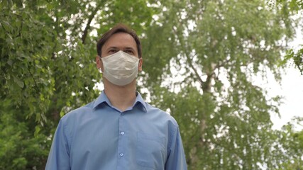 man goes to work in city in medical mask. man tourist protecting face from viruses. face shield on young man outdoors in park. go masked on face down street to store for shopping. covid 19