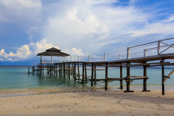 Beautiful scenery landscape view of long wooden jetty and white sand beach with blue sky ocean and green ocean