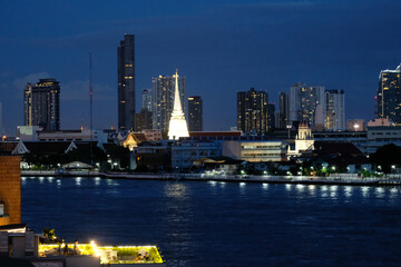 White pagoda amid surround buildings by a river in night light