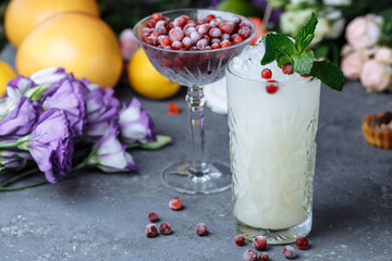 Summer fresh cold drinks. Ice lemonade with lemon decorated with cranberries and mint on an outdoor table. lemonade in a glass