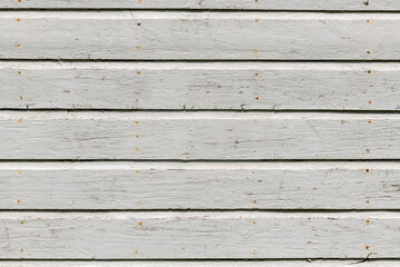 White wooden wall with rich texture, cracks, knots, and nails. Weathered timber planks background.